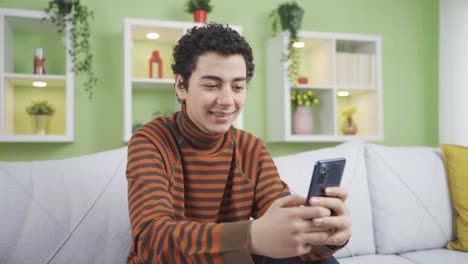 Happy-and-cute-boy-texting-on-the-phone-at-home.